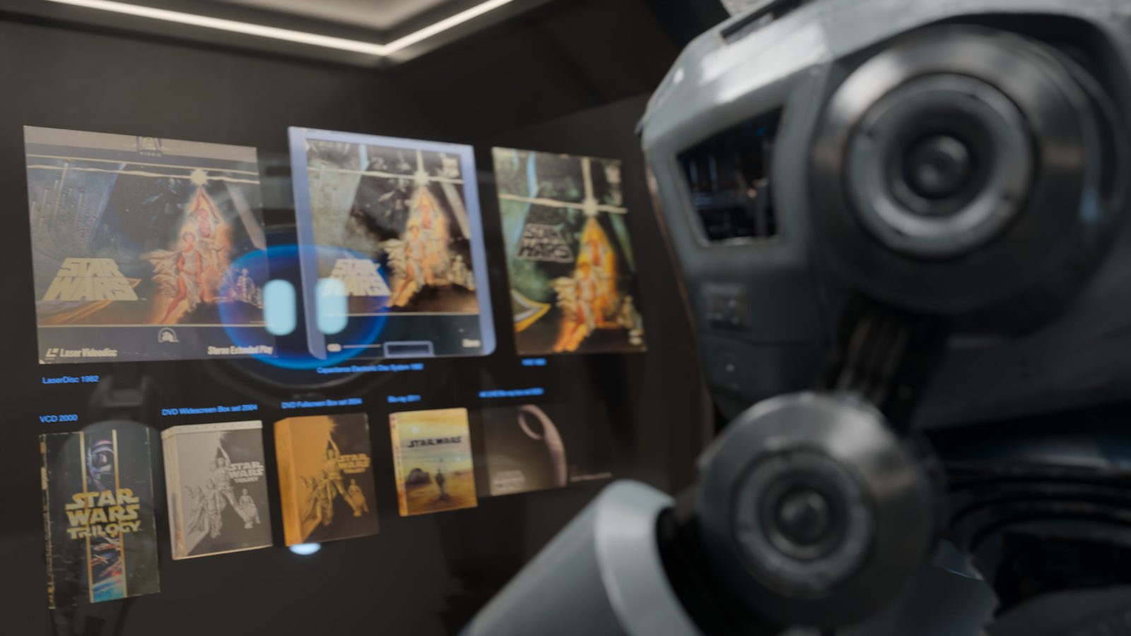 A droid studies the wall of Star Wars editions, from LaserDisc 1982 to 4K UHD